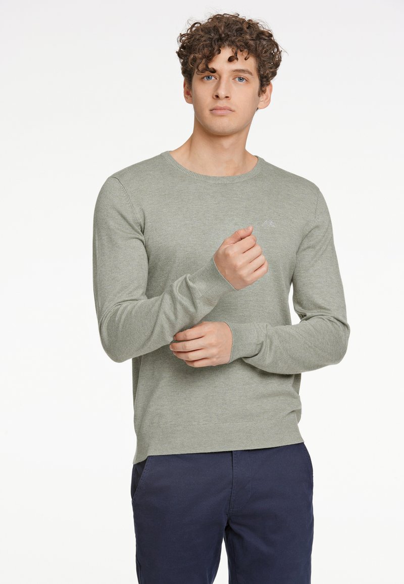 Maglione lungo verde chiaro a maniche lunghe realizzato in morbido tessuto a maglia, con scollatura rotonda e polsini a costine, caratterizzato da un piccolo logo sul petto.