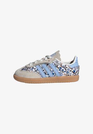 Basket basse avec rayures bleu clair, motif floral sur fond blanc, bout en daim beige et semelle en caoutchouc.
