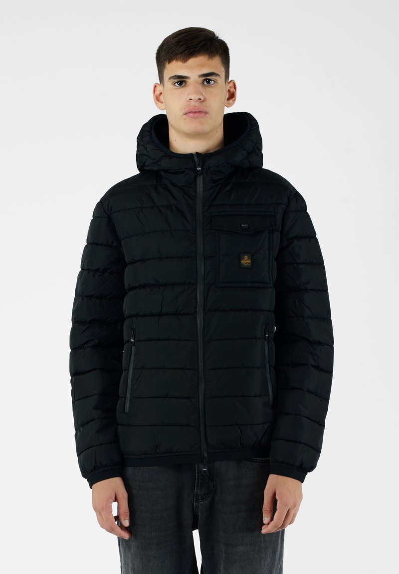 Giacca a vento nera, con zip frontale, grande cappuccio, design a righe orizzontali, tasche con zip e una piccola etichetta con logo sul petto.