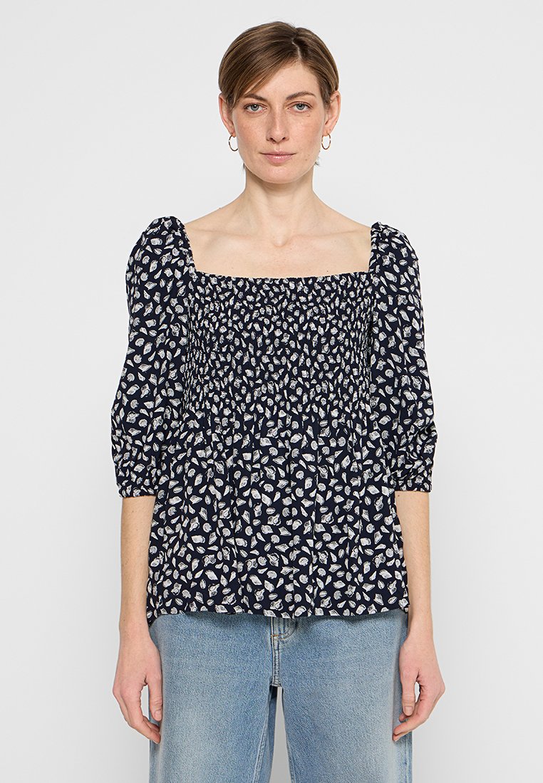 Dunkelblaue Bluse mit quadratischem Ausschnitt, puffartigen Ärmeln und einem gerafften Oberteil mit einem weißen Blattmuster. Strukturierter Stoff.