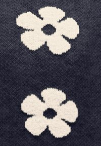 Pītā auduma tumši pelēkā krāsā ar baltām ziedu rakstām, katram ir pieci noapaļoti ziedlapiņas un centrāls aplis, radot tekstūru.