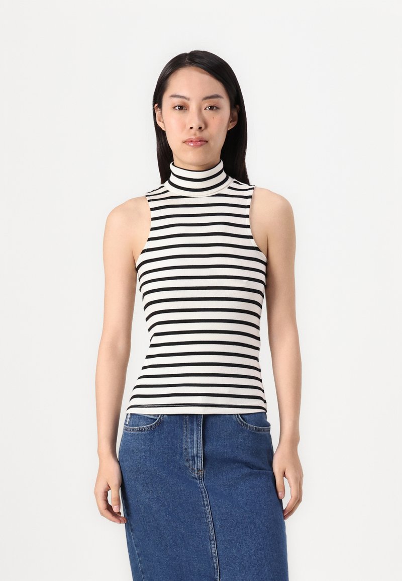 Camisola a maniche scoperte a righe in bianco e nero, texture a coste. Abbinata a una gonna di jeans blu, con tasche e design dritto.