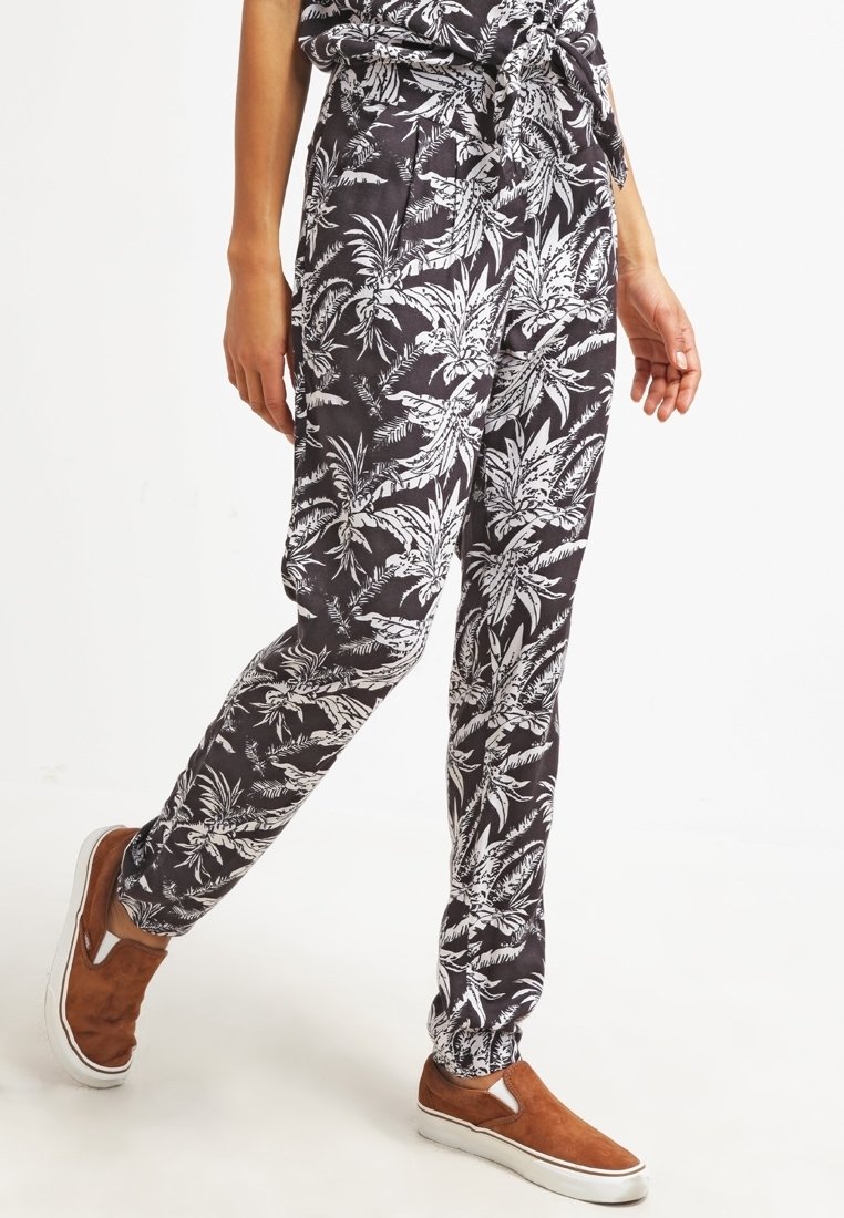 Zwarte gestreepte broek van lichtgewicht stof, met een witte bloemenprint, een trekkoord in de taille en taps toelopende benen. Gepaard met bruine instappers.