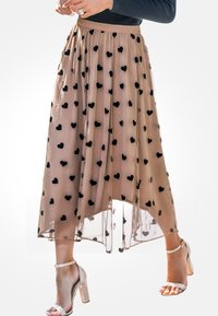Maxi rok in doorschijnend beige met zwarte hartjespatronen, met een verzamelde tailleband en een asymmetrische zoom. Gedirigeerd met doorzichtige sandalen met blokhak.