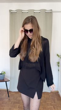 Svart langermet topp lagd over et tettsittende svart miniskjørt med sidesliss, kombinert med gjennomsiktige strømpebukser med prikker og mørke solbriller.