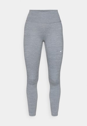 Leggings de sport gris clair avec une taille haute et une texture lisse. Présente un petit logo Nike blanc sur la cuisse gauche.