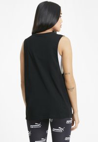 Svart ärmlös topp med avslappnad passform och mjukt bomullstyg. Baksidan är enkel utan dekorationer, kombinerad med mönstrade leggings.