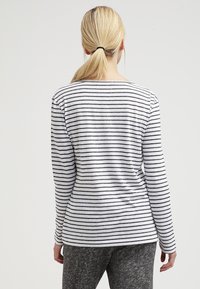 Gestreiftes Langarm-Shirt aus grauem und weißem Baumwollstoff. Mit einem runden Halsausschnitt und einer lässigen Passform, mit durchgehenden horizontalen Streifen.
