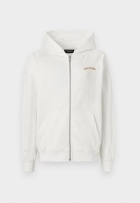 Bijela zip-up hoodie napravljena od mekane pamučne tkanine, s kenguruzim džepom, rebrastim manžetama i malim izvezenim logotipom u bež boji na grudima.
