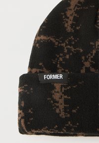Πλεκτός σκούφος σε μοτίβο καμουφλάζ μαύρου και καφέ, με ρεβέρ και μαύρη ετικέτα με τη λέξη "FORMER" σε λευκό κείμενο.