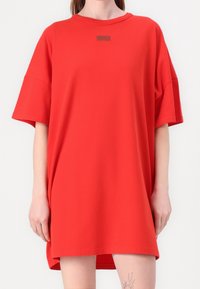 Czerwona, oversize koszulka z bawełny, z okrągłym dekoltem i krótkimi rękawami, z małym szarym logo na piersi.