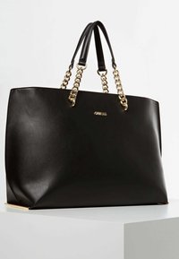 Zwarte leren tote tas met een gladde textuur. Voorzien van handgrepen met gouden ketting en een subtiel logo aan de voorkant. Rechthoekige vorm.