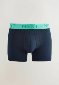 Tengerészkék pamut boxer rövidnadrág világos türkiz színű gumis derékkal, melyen vastag betűkkel a "KÖVETKEZŐ" felirat található.