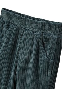 Pantalons en velours côtelé vert foncé avec une texture ribbed, une taille élastique et deux poches latérales. Présente des coutures visibles et une doublure subtile.