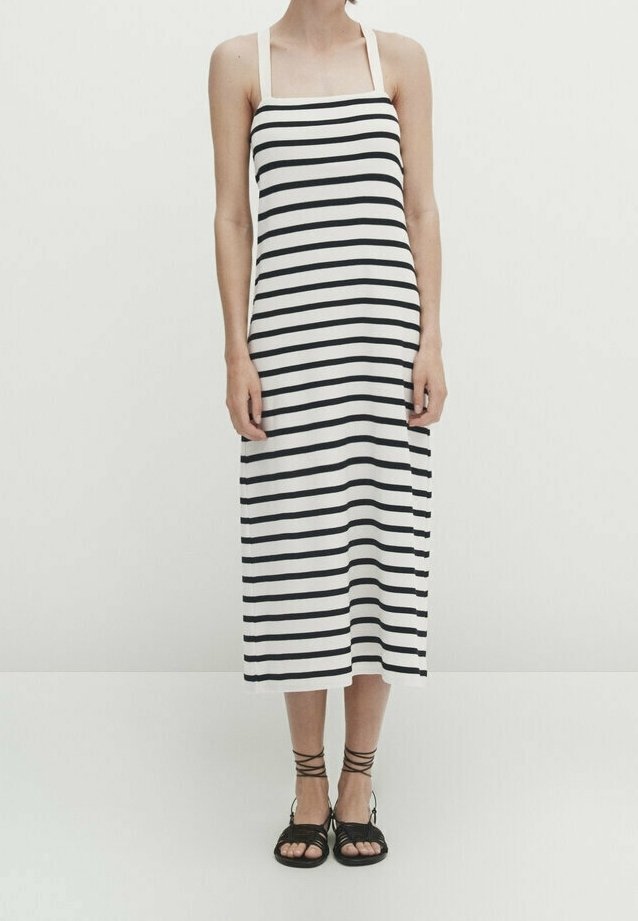 Robe midi à rayures noires et blanches avec un décolleté carré et de fines bretelles. Associée à des sandales noires à brides. Tissu en coton lisse.