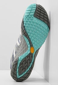 Sole Vibram v světle modré a šedé, s texturovaným vzorovaným povrchem pro trakci a stabilitu; zesílené okraje pro odolnost.