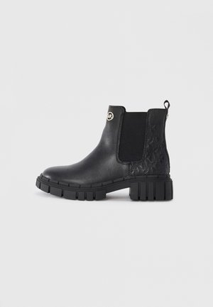 Bottines en cuir noir avec des panneaux latéraux en élastique, des accents texturés noirs et des semelles en caoutchouc épaisses. Présente un logo circulaire sur le côté.