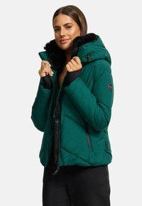 Green puffer jacket with a black faux fur collar, zip closure, and logo patch. Features quilted design and elastic cuffs for warmth.