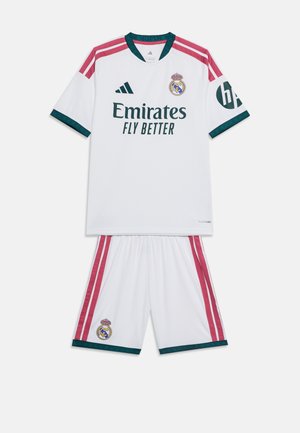 Camiseta y pantalones cortos blancos de fútbol del Real Madrid con rayas rosas, ribetes verdes, logotipos visibles de Adidas y patrocinadores.