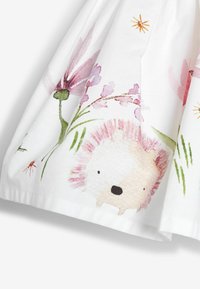 Weißer Baumwollstoff mit bunten Blumen- und Igelmustern, weichen Texturen und sanften, aquarellartigen Designelementen.