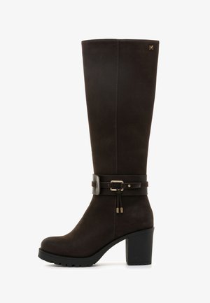 Stivale marrone in suede al ginocchio con tacco spesso nero. Presenta una cintura decorativa con fibbia e un accento dorato sul lato esterno.