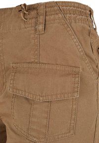 KHAKI cargo hlače iz teksturirane bombažne tkanine; imajo dve stranski žepi in varno pas z vrvico za zapiranje.