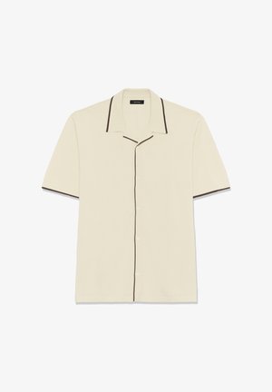 Krekls ar īsām piedurknēm krēmkrāsā ar strukturētu apkakli, brūnām apmalēm apkakles un piedurkņu malās, kā arī pogu aizdari priekšpusē.