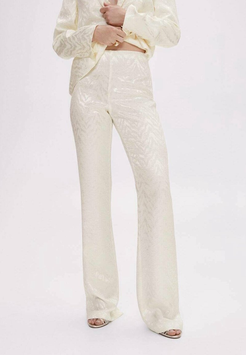 Kremowy zestaw składający się z dopasowanej bluzki i spódniczki z rozkloszowanymi nogawkami, wykonany z błyszczącego, teksturowanego materiału o subtelnym wzorze w zygzak.