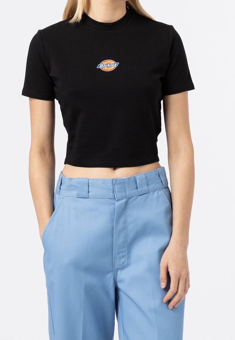T-shirt noire raccourcie à manches courtes avec un logo Dickies multicolore sur la poitrine. Associé à un pantalon taille haute bleu clair.