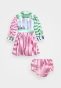 Pruhované šaty a sladěné kalhotky. Šaty mají růžové, bílé, zelené a modré pruhy, límec, dlouhé rukávy a plisovanou sukni.