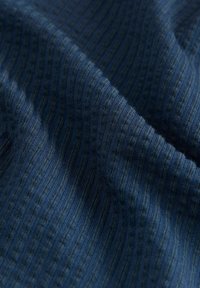 Texturerad mörkblå tyg med vertikala ribbmönster och en slät yta, som visar ett mjukt, vävt textilutseende.