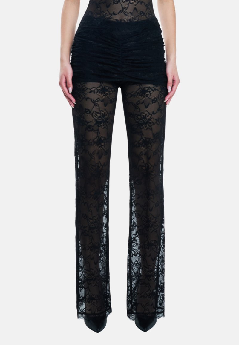 Kant pantalons met een doorschijnend, zwart bloemenpatroon, met een gerimpelde tailleband en brede, uitlopende pijpen. Geaccentueerd met zwarte spitse hakken.