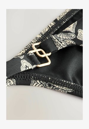 Crne gaćice od bikinija s cvjetnim uzorkom u krem boji, s naglaskom na zlatnu metalnu opremu. Tkanina je glatka s detaljnim šavovima.