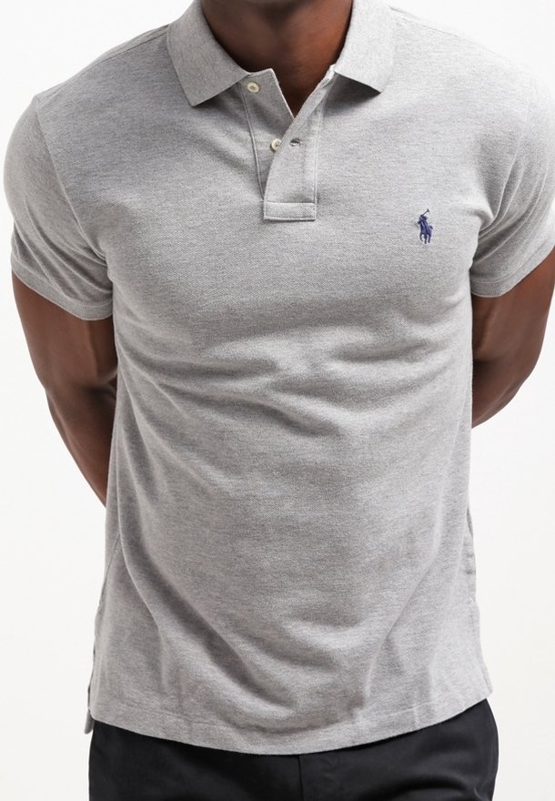 Polo gris avec un col, des manches courtes et une patte de boutonnage à deux boutons. Présente un petit logo bleu sur la poitrine. Texture de tissu douce.