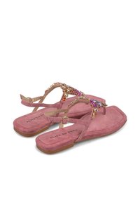 Tongs en daim rose avec une large bride ornée de gemmes et de perles colorées, dotées d'une semelle plate et d'une boucle à la cheville pour un ajustement.