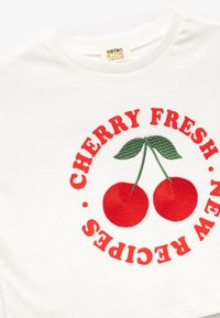 Witte katoenen t-shirt met rode geborduurde tekst "CHERRY FRESH NEW RECIPES" en twee rode kersen met groene bladeren in het midden.