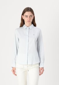 Camicia button-up a righe blu chiaro con colletto, maniche lunghe e piccolo logo sul petto. Realizzata in un tessuto liscio con una vestibilità su misura.