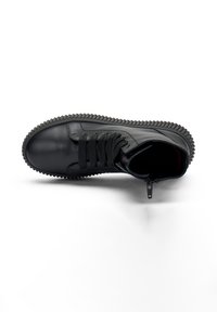 Zapatilla alta de cuero negro con suela texturada, sistema de cordones en la parte delantera y cremallera lateral. Presenta un color interior en contraste. Acabado liso.