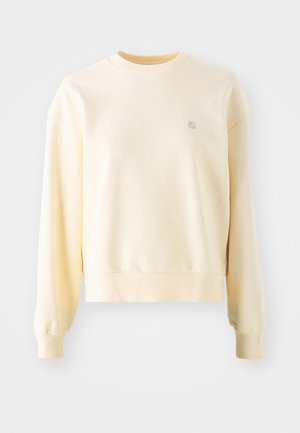 Hele kollane pusak, millel on pikad varrukad, ümar kaelus, soonilised mansetid ja väike logo rinnal. Valmistatud pehmest, tekstureeritud kangast.