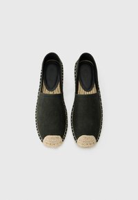 Sorte slip-on sko med en tekstureret overdel og en vævet, beige tåkappe. Har en kontrasterende syet kant og en flad sål.