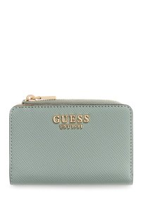 Portefeuille vert texturé avec logo doré "GUESS EST 1981" sur le devant, doté d'une fermeture éclair et d'une forme rectangulaire.