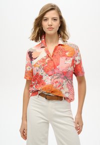Chemise à manches courtes avec un imprimé floral vif mettant en avant des couleurs rose, orange et bleue. Fabriquée à partir d'un tissu léger avec un col.