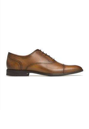 Chaussure habillée en cuir marron avec une finition lisse, bout arrondi, coutures discrètes et un petit talon en caoutchouc noir. Fermeture à lacets.