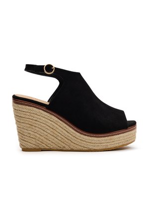 Sandalia de cuña de ante negro con punta descubierta, correa en el tobillo ajustable y suela de yute trenzado. La altura combina un diseño casual y elevado.