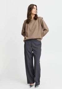 Brown loose-fitting top with a square neckline, paired with gray pinstriped trousers and metallic pointed-toe heels. Smooth texture, relaxed fit.
