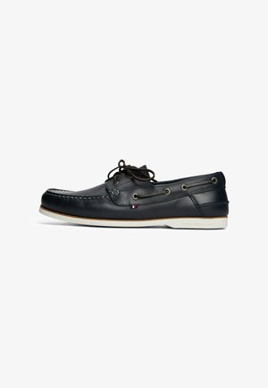 Marineblaue Lederschuhe mit runder Zehenform, braunen Schnürsenkeln, Metallösen und weißer Gummisohle, die das Markenlogo an der Ferse trägt.