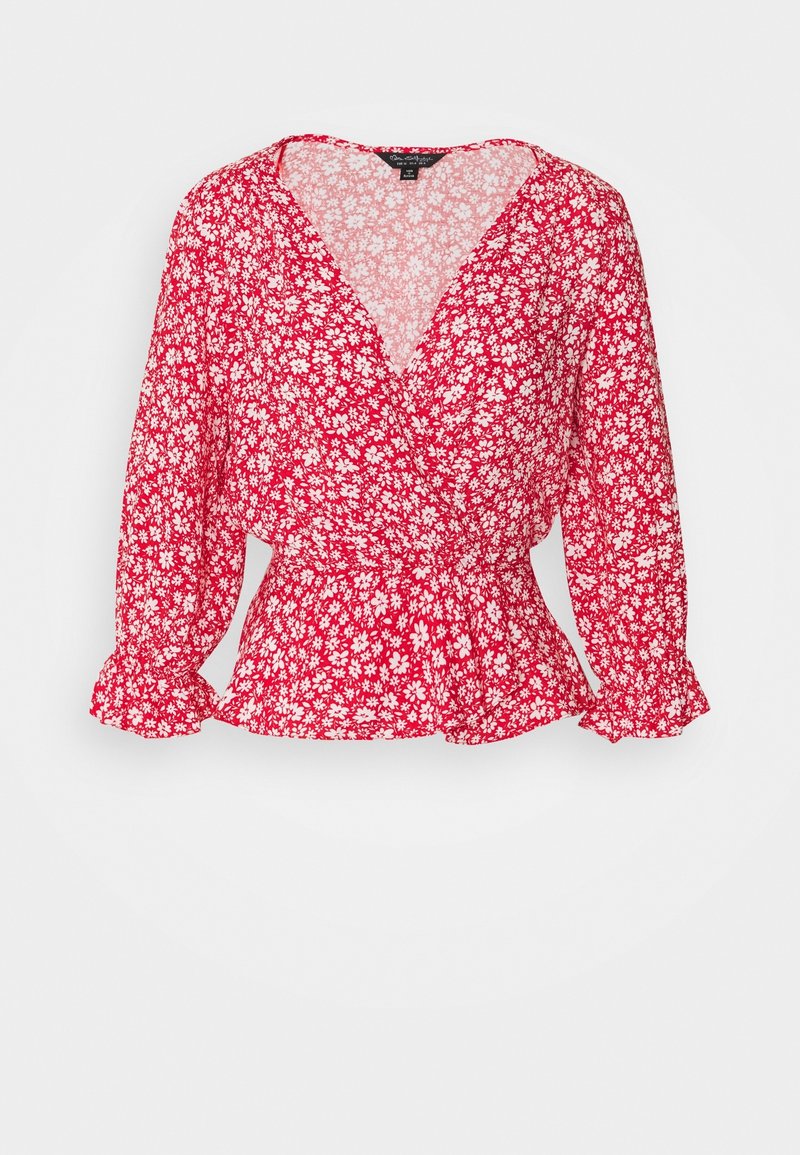 Blouse à manches longues à fleurs rouges, avec un décolleté en V, une taille froncée et des motifs de marguerites blanches sur un tissu léger.