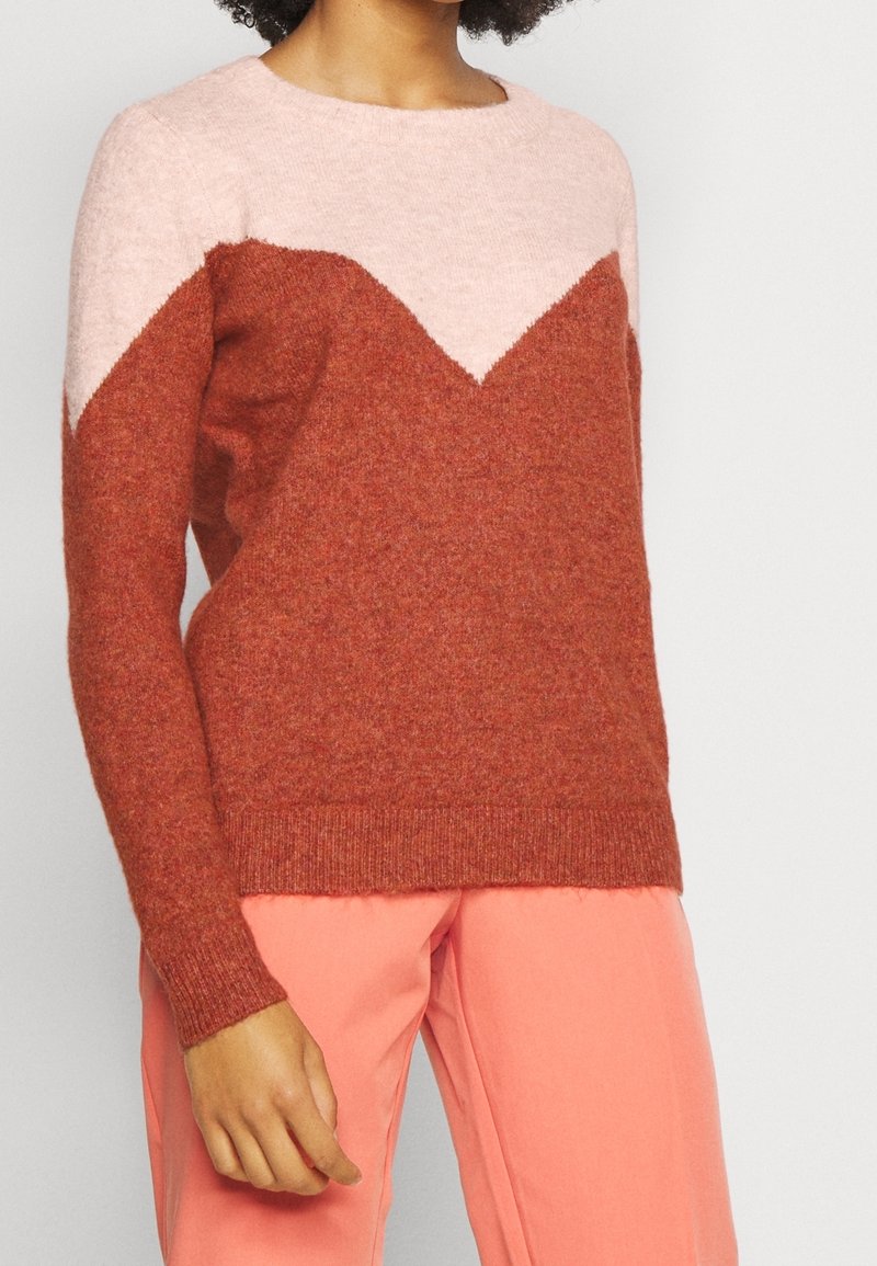 Sweter w pięknym różowo-rdzawym kolorze z wzorem w jodełkę. Wykonany z miękkiego materiału, z okrągłym dekoltem i ściągaczami przy rękawach.