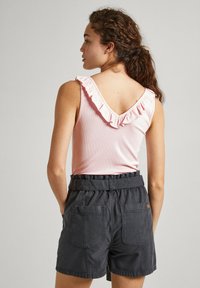 Top a righe rosa con scollatura arricciata abbinato a pantaloni corti neri a vita alta con due tasche frontali e vita con cintura.