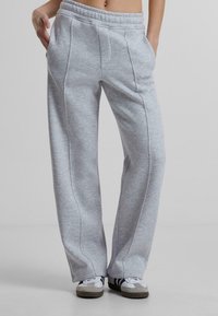 Hellgraue Sweatpants mit elastischem Bund, seitlichen Taschen und kontrastierender Naht. Weiches Material mit lässigem Schnitt.